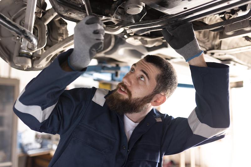 Bilmekaniker som mekar med bil